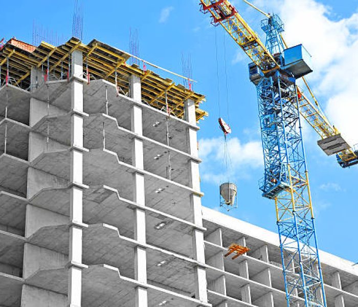 Crane and building under construction against blue sky